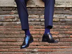 Uomo con calzini blu a pois bianchi e scarpe nere lucide. Un perfetto abbinamento calzini scarpe uomo per un look elegante.