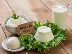 Serek wiejski, kulka mozzarelli i ser w kształcie stożka na sałacie, obok szklanki mleka. Etykieta głosi "lactose free", co oznacza brak laktozy.