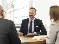Anwalt für Versicherungsrecht bietet kostenlose Erstberatung. Drei Personen im Gespräch am Tisch.