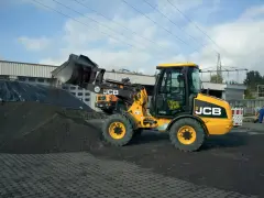 Żółta ładowarka JCB 406 z podniesioną łyżką, gotowa do pracy. Dane techniczne tej maszyny pozwalają na efektywne przenoszenie materiałów.