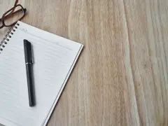 Notatnik z długopisem i okularami, gotowy do spisania opinii o uczniu.