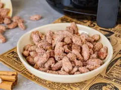 Schüssel mit gerösteten Mandeln, die mit Zimt und Zucker bestreut sind. Ein gesunder Snack, der gut schmeckt.