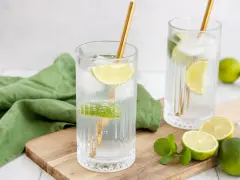 Erfrischende Drinks: Zwei Gläser mit Eis, Limettenscheiben und goldenen Strohhalmen. Perfekt zum **Wodka mischen** an einem warmen Tag.