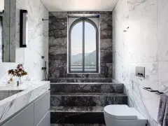 Bagno di lusso con vasca doccia in muratura, rivestimenti in marmo e vista panoramica.
