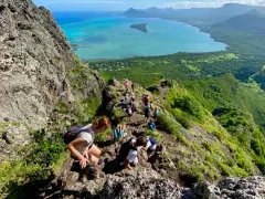 Grupa turystów wędruje po skalistym szlaku na Le Morne Mauritius, podziwiając zapierający dech w piersiach widok na turkusową lagunę i zielone wzgórza.