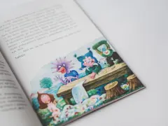 Smok Luomił i tajemnice złości. Ilustracja z książki przedstawia wesołe stworki przy stole, a obok nich dziewczynkę.