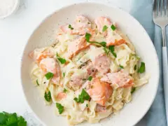Pasta cremosa con trozos de salmón rosado y perejil fresco. Un plato delicioso y nutritivo.