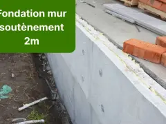 Construction d'un mur de soubassement de 2m, avec des briques rouges et des matériaux isolants.