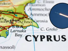 Mapa Cypru z zaznaczonym lotniskiem w Larnace. W okręgu widoczny start rakiety kosmicznej.