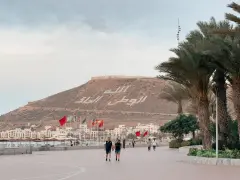 Spacerem po promenadzie w Agadirze, z widokiem na miasto i napisem na wzgórzu. Czy Agadir jest bezpieczny? Tak, wygląda na spokojne miejsce.