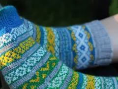 Två par stickade sockor med färgglatt sticka mönster med två färger i blått, gult, grönt och vitt.