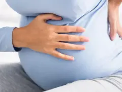 Kobieta w ciąży trzyma się za bok, odczuwając ból. Może to być kolka nerkowa w ciąży.
