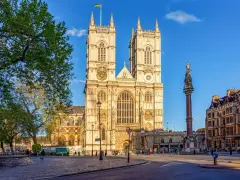L'abbaye de Westminster, majestueuse et illuminée par le soleil, se dresse fièrement avec ses tours jumelles. Une colonne commémorative se dresse à droite.