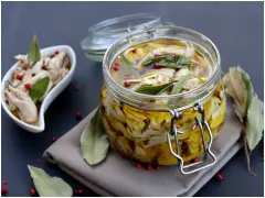 Un vasetto di antipasto piemontese di carne bianca sott'olio, con erbe aromatiche e pepe rosa. Accanto, una ciotolina con lo stesso saporito antipasto.