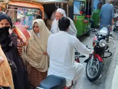 Ludzie na ulicy w Pakistanie, wśród nich kobiety w hidżabach i dzieci. Czy pakistan jest bezpieczny? Tłum na targu, ruchliwa ulica.