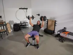 Homme faisant un exercice banc de musculation avec haltères.