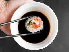 Pałeczkami zanurzam sushi w sosie kabayaki.