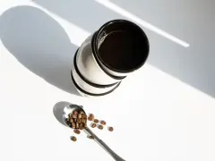 Stos kawy w filiżankach i łyżka z ziarnami kawy. Zastanawiasz się, ile kofeiny ma kawa w 100 ml?