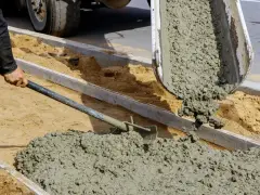 Robotnicy wylewają świeży beton z samego piasku i cementu, tworząc nowy chodnik.