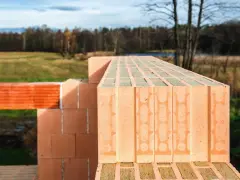 Nowa ściana z pustaków ceramicznych rośnie na tle jesiennego krajobrazu.
