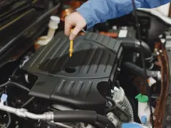 Mechanik sprawdza poziom oleju w silniku Peugeot 508. Wymiana oleju w skrzyni manualnej to ważny element dbania o auto.
