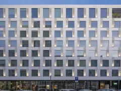 Nowoczesny hotel Puro Warszawa z licznymi oknami i pionowymi podświetlanymi elementami fasady.