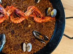 Paella de marisco con gambas rojas, mejillones y almejas sobre arroz dorado.