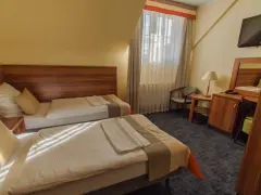 Pokój w zajazd u dziadka: dwa wygodne łóżka, stolik nocny z lampką, biurko z lustrem i krzesłem, telewizor.