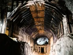 Wnętrze kopalni, drewniane wsporniki tworzą tunel, który prowadzi do jasnego otworu. To część kompleksu Rize.