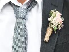 Elegancki krawat do ślubu w kratkę, biała koszula i butonierka z różową różą.