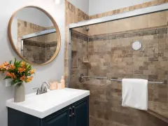 Salle de bain moderne avec douche carrelée, lavabo et miroir rond. Idéal pour nettoyer VMC et profiter d'un espace sain.