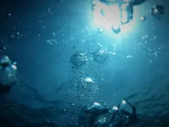 Bąbelki powietrza unoszą się w głębinach, gdzie światło słoneczne przebija się przez wodę, oświetlając grunty pod wodami powierzchniowymi płynącymi.