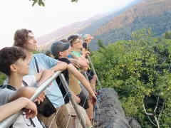 Grupa młodych ludzi na szlaku, podziwiająca widok. Idealne miejsce na pierwsze wyprawy trekkingowe dla początkujących.