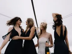 Sorelle della sposa, con abiti neri eleganti, celebrano il matrimonio con champagne. Accessori per abito nero matrimonio perfetti per un look sofisticato.