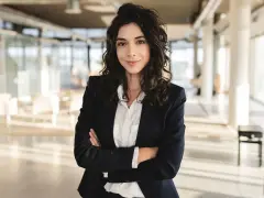 Kobieta w marynarce i białej koszuli, idealnie wpisująca się w **business casual dress code**, pewnie patrzy w obiektyw.