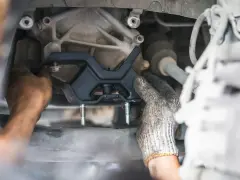 Mechanic installing a new engine mount. This repair is essential for smooth driving and can impact motor mount replacement cost.