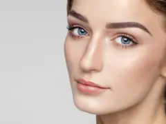 Delikatne rysy twarzy, podkreślone subtelnie zaznaczone mięśnie brody, błękitne oczy i perfekcyjny makijaż.