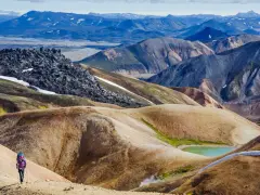 Un randonneur solitaire explore les paysages colorés et volcaniques de Landmannalaugar, un trek inoubliable en Islande.
