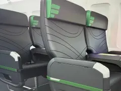 Rows of black airplane seats with green accents. Does Frontier have first class? These seats look comfortable, but it's unclear if they are first class.