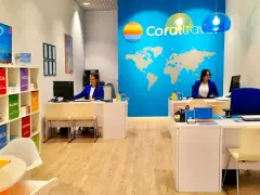 Biuro podróży Coral Travel z pracownicami za ladą i mapą świata na ścianie.