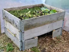 En kompost av pallkragar fylld med trädgårdsavfall. Enkel och effektiv lösning för att bygga kompost.