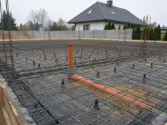 Przygotowania do wylania fundamentu tradycyjnego: zbrojenie, folia izolacyjna i rury kanalizacyjne.