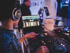 Młody DJ ćwiczy na sprzęcie, słuchawki na uszach. To świetny moment na rozpoczęcie kursu DJ online i naukę miksowania.