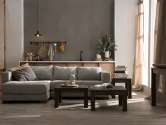 Sofá seccional en color greige, mesas de centro de madera oscura, estanterías y cortinas de lino.
