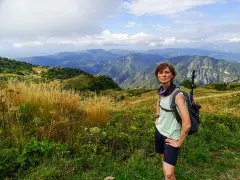 Donna con zaino e bastoncini da trekking ammira il panorama montuoso, un'emozione delle camminate FVG.