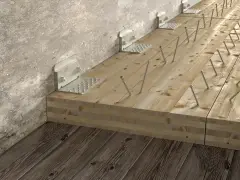 Wzmocnienie belek drewnianych stropu za pomocą metalowych kątowników i wkrętów.