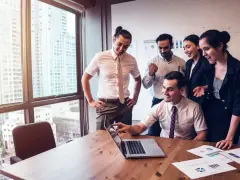 Zespół świętuje sukces. Mężczyzna, który jest business development managerem, wskazuje na ekran laptopa.