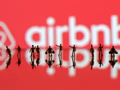 Małe figurki ludzi na tle logo Airbnb. Zastanawiasz się airbnb co to? To platforma do rezerwacji noclegów.