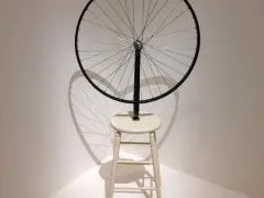 Roue de vélo fixée sur un tabouret, une œuvre emblématique de Marcel Duchamp, projetant une ombre fascinante.