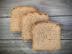 Drei Scheiben **Vollkornbrot** aus der **Kastenform** liegen auf rustikalem Holz.
